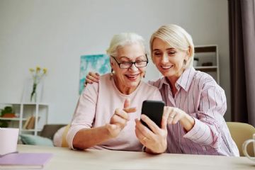 signora giovane aiuta anziana con il telefonino